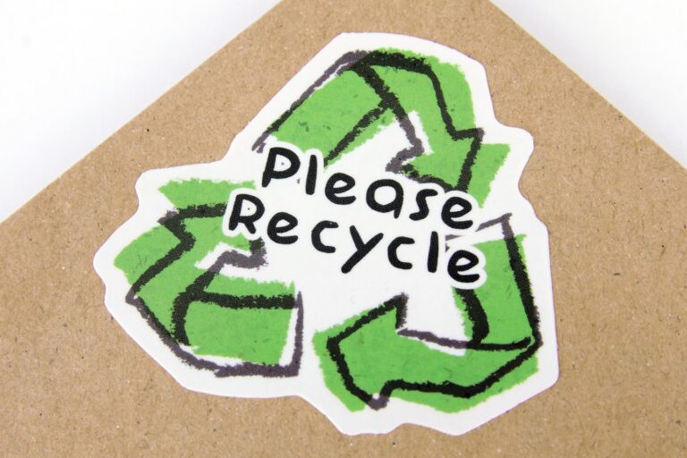 Die cut biodegradable paper sticker with please recycle logo applied to kraft paper envelope