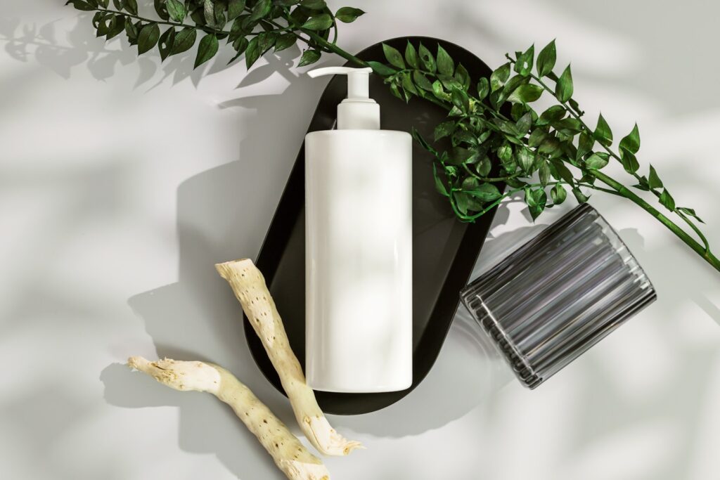 a white vase with a white candle and a plant on a white surface