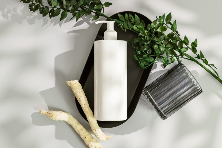 a white vase with a white candle and a plant on a white surface