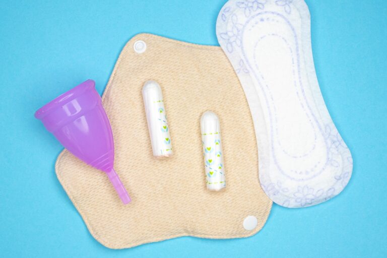 Menstrual products and supplies (pads, tampons, menstrual cups) on a colorful background.